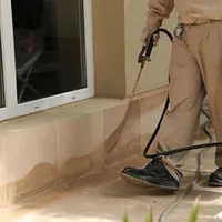 General pest control technician spraying exterior perimeter around a home in Evansville, IN