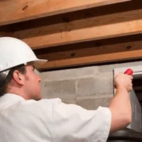 Termite inspection technician checking a basement wall and framing for termite activity in Evansville, IN